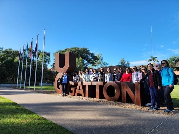 Group of people stand next to UQ Gatton sign